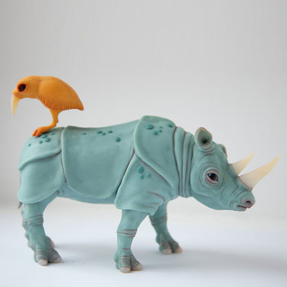 Sculpture called "perfect marriage". It is a gray-blue realistic rhinoceros, on his back sits a yellow-orange bird with a large beak. The sculptural group is made of polymer and epoxy, the rhinoceros hooves, horns and beak of the bird are made of translucent white polymer