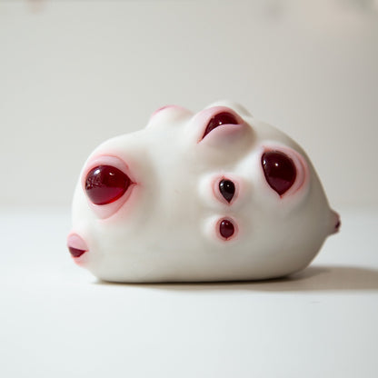 Strange and unusual sculpture, potato shape creature with number of red eyes. Alien lifeform albino fantasy creature