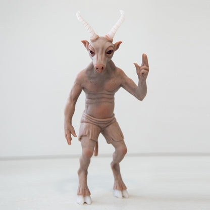 The Maryland Goat Man. A well-known mythical figure, half goat half man. He has legs with hooves, a goat-like face, horns, and a human body. The sculpture is made of brown polymer, the horns and hooves are the color of bone