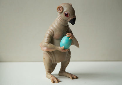 Pingin like alien character, Egg Thief. He has beige skin, round ears, red eyes and small beaver-like tail. Also he keeps blue egg in hands. Sculpture made from polymer clay and epoxy.
