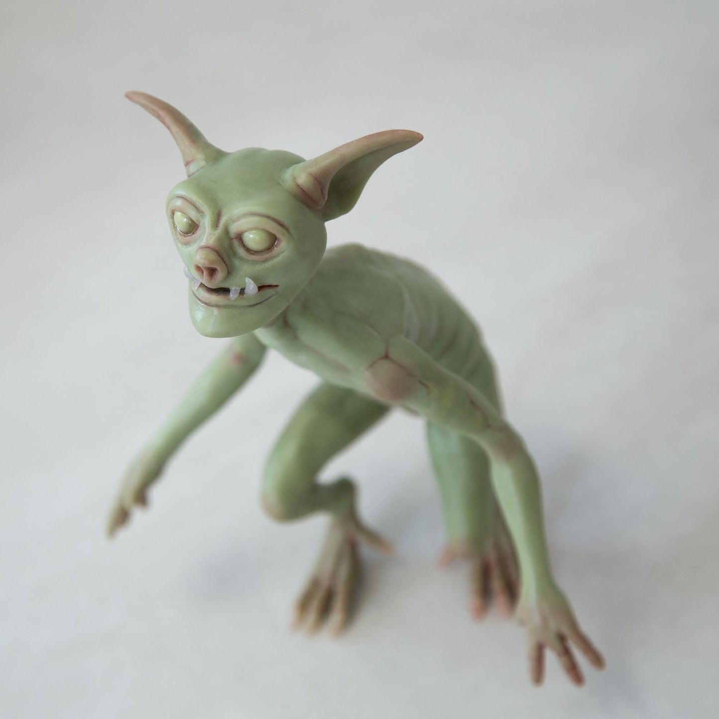 Cute green goblin sculpture with glow in the dark eyes, were created by Abigail Larson and made in our team.