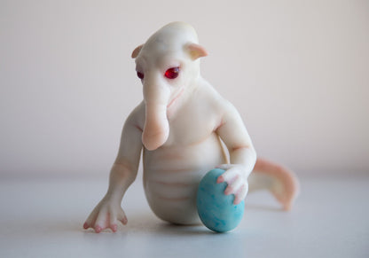 A fictional character, a water elephant - a fish - a merman. He has white skin, a fish body, a human torso, a head with a trunk. An alien life form. Unique design and handmade