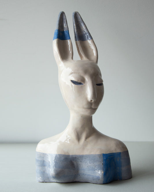 Ceramic glazed Hare woman sculpture bust with gordial face. Sculpture made from ceramic mass, has hare ears. Colors used are white, light blue and blue.