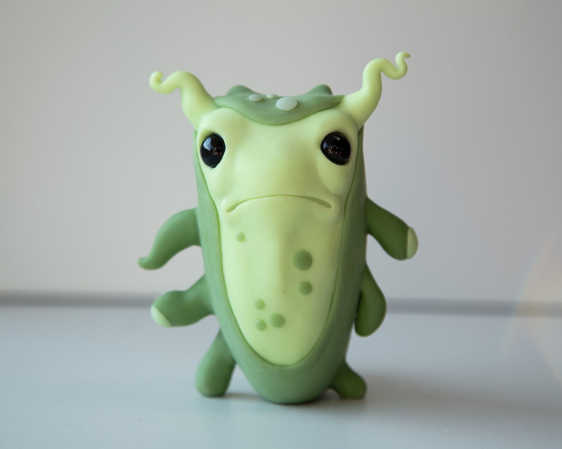 Small and cute microbe - germ figurine in cartoon anime style. Green and light green colors, polymer clay medium, eyes are black and made from epoxy