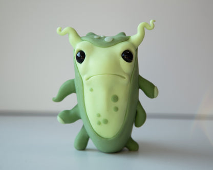 Small and cute microbe - germ figurine in cartoon anime style. Green and light green colors, polymer clay medium, eyes are black and made from epoxy