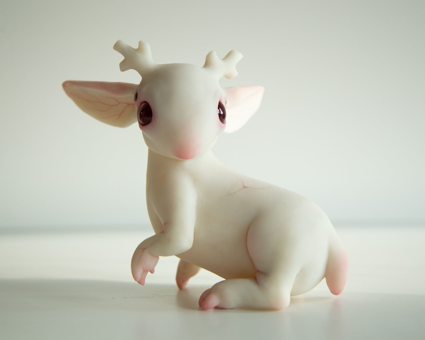 White jackalope figurine with pink accents on a light background