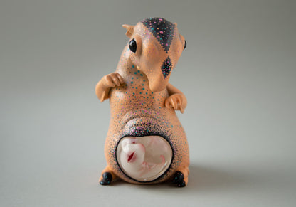 Sculpture of an alien Tapir with a transparent belly, from which the embryo is visible, hand-painted with an abstract space ornament. The colors used are: black, orange, blue, gray. The sculpture is made of acrylic, acrylic paints and varnish were used