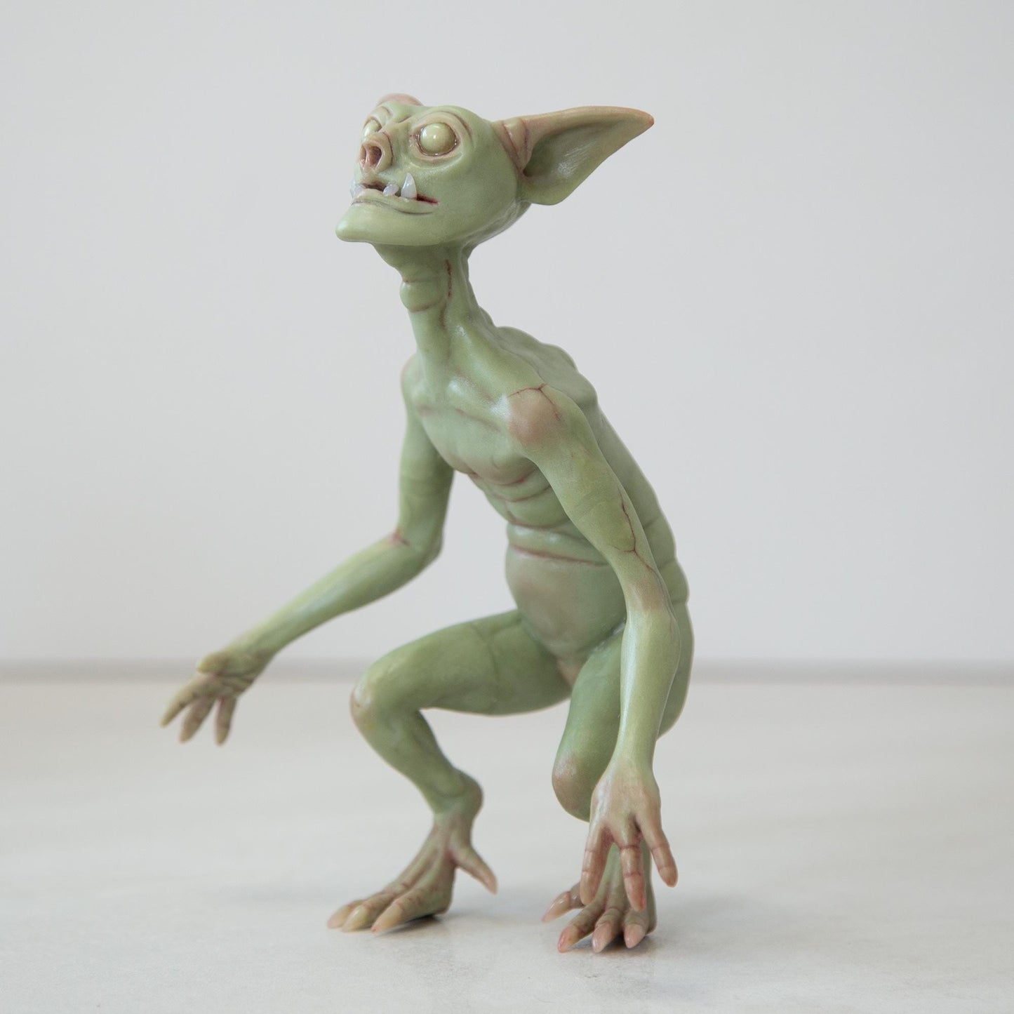 Cute green goblin sculpture with glow in the dark eyes, were created by Abigail Larson and made in our team.