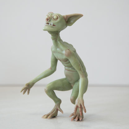 The green goblin, sitting on his hind legs, is thin and sinewy, has protruding teeth on his lower jaw, pointed large ears and glowing eyes. Character Abigail Larsen, made in our team