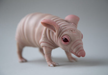Fantasy mouse figurine, thick body with folds of skin, small red eyes and wrinkled nose. The sculpture is made of beige-pink polymer
