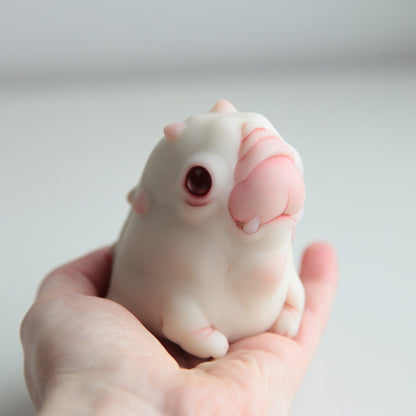 A cute little creature, an alien warthog. It looks like a cross between a pig and a puppy, it has a cute face, small fangs and thick little paws. The sculpture is made in white with red eyes