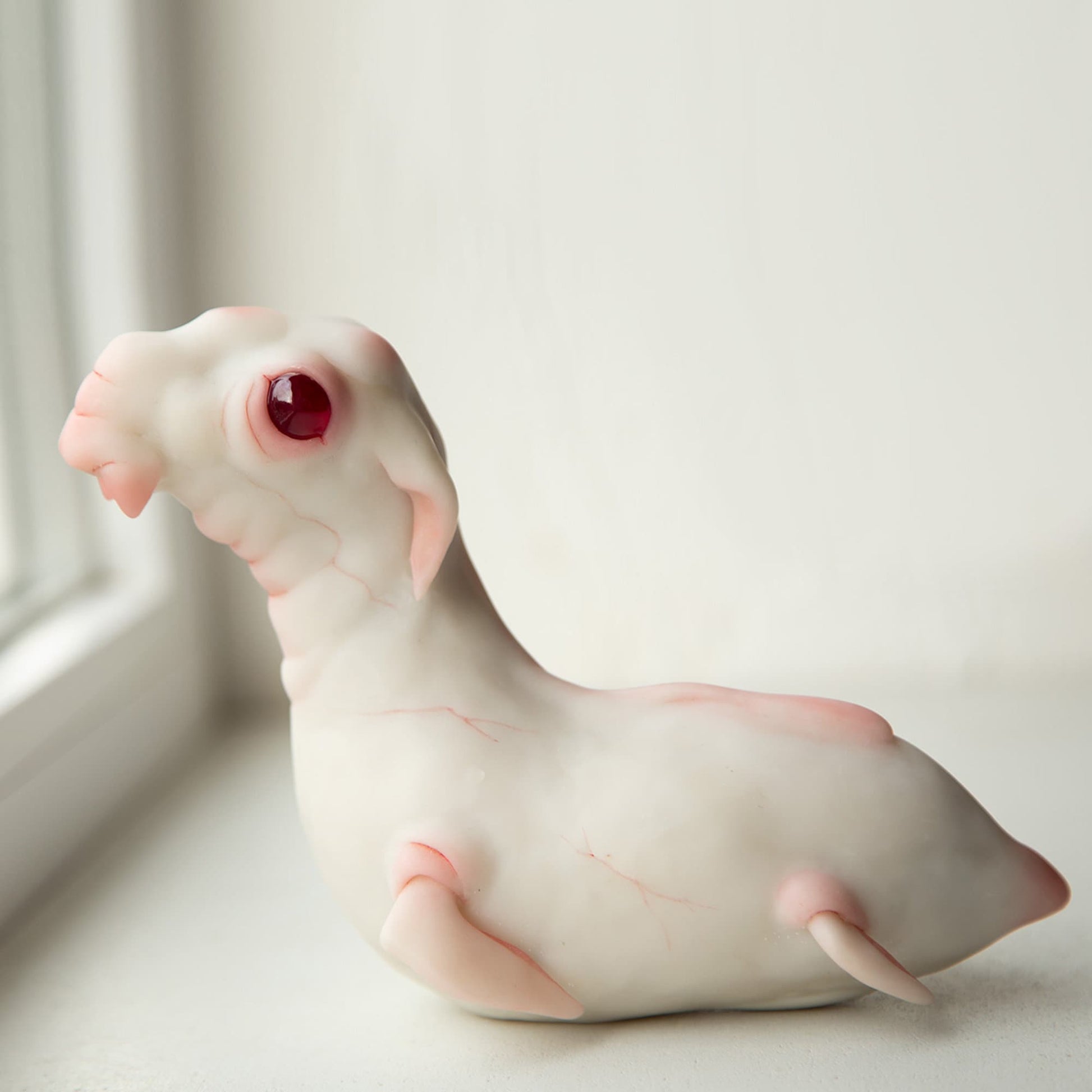 Loch Ness Monster in our cute interpretation. It has white marble skin with red veins, a cute baby face and 4 fins on the sides of the body like a manatee, kind red eyes