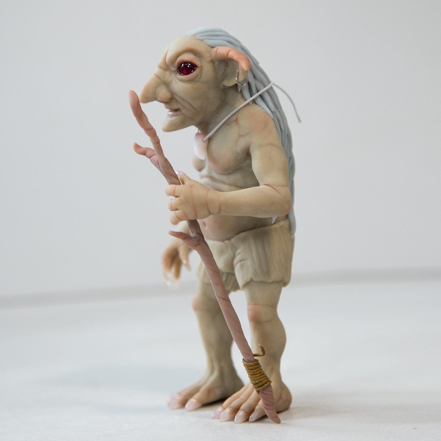 Sculpture of a character from Native American legends, Pukwudgie. This is a small goblin - an old man, he has a staff, long ears and needles like a hedgehog on his back. Green-gray skin, a smiling face, a hooked nose.